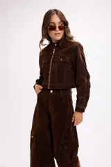 Chaqueta corta de terciopelo negro con efecto desgastado en tono azulado, cuello mao, cierre frontal metálico y bolsillos frontales con tapa y botón.