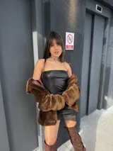 Vestido lencero corto de efecto cuerina negro, sin tirantes y con detalle de encaje en el borde inferior.