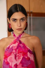 Vestido midi con estampado abstracto en tonos fucsia, rosa y violeta. Presenta un diseño de cuello halter cruzado con detalle de collar integrado y espalda descubierta.