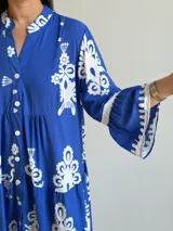 Vestido largo color azul con estampado ornamental en color blanco, escote en V con botones frontales y mangas tres cuartos con volados.