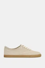 Zapatillas tipo deportiva confeccionadas en serraje color beige, con diseño barefoot de puntera amplia, suela flexible efecto engomado y cierre mediante cordones al tono.
