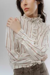 Camisa de corte clásico con estampado de rayas verticales, cuello alto con volados frontales y mangas largas con puños con volados.