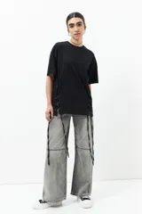 Remera negra de manga corta, corte oversized, con cuello redondo y cordones ajustables a los laterales.