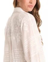 Camisa de algodón broderie color blanco, marca Liv Los Ángeles. Cuello con solapa, abertura central con botones y mangas ¾ amplias.