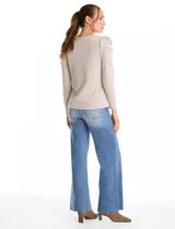 Buzo de tejido soft color gris oscuro, con cuello redondo y mangas largas. Presenta hombros con diseño plisado y detalle de perlas aplicadas.