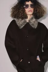 Abrigo confeccionado en hilatura con lana, de corte recto y diseño minimalista. Presenta cuello solapa con aplicación de pelo sintético desmontable, cierre frontal con botones y bolsillos de plastrón en el delantero.