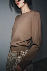 Jersey básico de cuello redondo y manga larga, confeccionado en hilatura de lana 100% con acabado de punto liso.