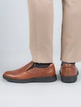 Zapato tipo slip on Hush Puppies de cuero color marrón, con suela negra de poliuretano con tecnología Spinal y plantilla Dual Fit.