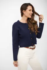 Saco de punto azul marino con cuello redondo, cierre frontal de botones y dos bolsillos delanteros tipo parche. Presenta mangas largas con puños acanalados y un diseño corto y estructurado.