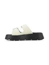 Sandalia de cuero graneado color blanco off-white, con suela chunky negra de poliuretano y doble tira ajustable con hebillas metálicas.