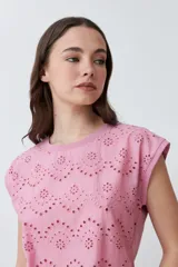 Blusa de algodón color rosa pastel con frente de tela broderie, cuello redondo y mangas cortas con terminación al corte.