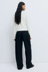 Buzo de punto trenzado color blanco, con cuello redondo, manga larga y un pequeño corazón bordado en el pecho. Presenta terminaciones acanaladas en cuello, puños y ruedo.