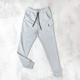 Pantalón de jogging gris claro con puños ajustados, cintura elástica con cordón negro y bolsillos laterales.