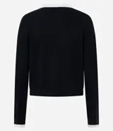 Cardigan de punto color blanco con detalles en negro en cuello, puños y tapeta frontal. Presenta cierre frontal con botones perlados y dos bolsillos delanteros falsos con solapa bicolor.