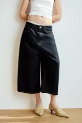 Bermuda baggy de denim azul oscuro con tiro medio, trabillas, cinco bolsillos y costuras en contraste. Cierre frontal con cremallera y botón metálico.