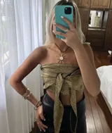 Top negro con diseño cruzado en el frente, estilo halter y con detalles de tachas doradas.