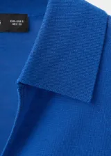 Buzo de punto color azul, con cuello polo y manga corta, de diseño recto.