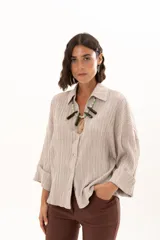 Camisa de silueta relajada con cuello clásico, confeccionada en tela liviana con textura. Presenta mangas amplias con caída fluida y un tablón escondido en la espalda que aporta mayor amplitud al calce.