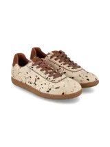 Sneaker deportivo de cuero con pelo, con estampado tipo animal print de manchas en tonos marrones y negros sobre base cruda. Presenta suela de goma color miel, cordones marrón y detalle de talón en cuero liso.