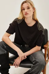 Remera de algodón color negro, de corte holgado y manga corta, con detalle de bordado en forma de plumas en los hombros.