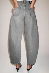 Jeans de tiro medio con diseño de pierna tipo balloon y largo al tobillo. Presenta cinco bolsillos, cierre frontal con cremallera y botón, y un acabado con efecto lavado.
