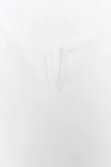 Top corto blanco confeccionado en mezcla de algodón, con escote redondo pronunciado con pequeña abertura central y manga corta estilo casquillo.