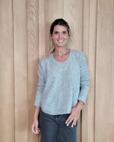 Sweater de punto color beige, con cuello en V, manga larga con puños acanalados y diseño holgado.