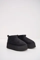 Bota corta tipo ugg de color negro, con plataforma alta y suela dentada. Presenta costuras reforzadas y tirador en la parte trasera.