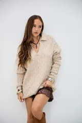 Sweater de punto trenzado color beige, con cuello en V y cuello polo, de manga larga y corte holgado.