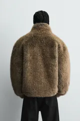 Abrigo corto de corte relajado confeccionado en tejido con efecto pelo. Presenta cuello subido, cierre frontal con cremallera, mangas largas con puños elásticos y bajo ajustable con elástico interior. Incluye bolsillos laterales en la cadera y un bolsillo interior.