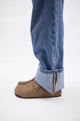 Zueco de cuero vacuno en color marrón oscuro, con diseño de punta cerrada, ajuste mediante hebilla metálica lateral y suela de corcho con base de goma.