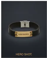 Pulsera de banda de cuero negro con placa central de acero en tono dorado, decorada con un diseño de guarda griega y remaches laterales. Cuenta con un cierre de seguridad de acero inoxidable.