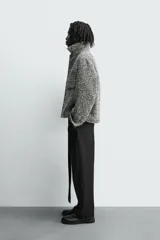 Sobrecamisa de corte relajado con textura de tejido estructurado en color gris y negro. Presenta cuello clásico, cierre frontal con botones, mangas largas con puños abotonados y bolsillos de plastrón en el pecho.