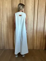 Vestido largo de lino color beige, sin mangas, con escote en V, bolsillos laterales y tajos en los laterales del ruedo.