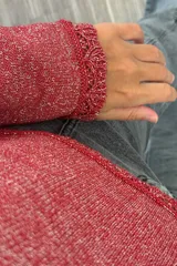 Sweater tejido de punto en color rojo con destellos de lurex. Presenta cuello redondo, mangas largas con terminación acampanada y detalle de borde festoneado en puños y ruedo.