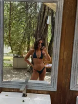 Top de bikini triangular negro con tirantes finos para atar al cuello y en la espalda, y detalle de argolla de resina carey en el centro.