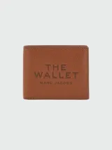 Billetera Marc Jacobs modelo The Billfold, color negro, con diseño plegable de cuero texturizado y estampado frontal en relieve con el texto "The Wallet" y la marca.
