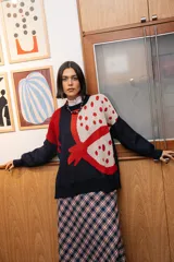 Buzo tejido de punto con diseño gráfico de granada en colores rojo y crema sobre base azul marino. Presenta silueta oversize, cuello redondo y calce relajado.