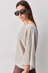 Sweater de punto liviano negro, con escote bote y mangas amplias de largo tres cuartos que aportan una silueta relajada y fluida.