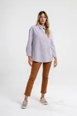 Camisa color lila de corte recto, con cuello clásico, cierre frontal con botones dorados y mangas largas.