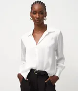 Camisa de satén color blanco, de manga larga con puños anchos, cuello inglés y cierre frontal de botones.