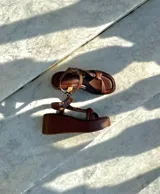 Sandalias de plataforma doradas, con suela ancha y tiras anchas cruzadas en el empeine y una tira ajustable en el tobillo.