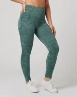 Calza deportiva ajustada color verde oscuro con estampado texturizado o jaspeado. Presenta cintura alta de doble tela sin elástico visible.