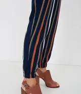 Pantalón de viscosa con rayas verticales en azul marino, blanco y naranja. Tiene bolsillos laterales, cintura elástica con cordón ajustable y tobillos ajustados con elástico.