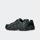 Championes Asics modelo Gel 1130, color blanco con detalles plateados y verde oscuro. Diseño retro inspirando en el running con tecnología GEL en el talón.