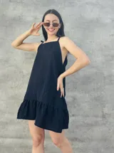 Vestido corto negro con textura de lunares, breteles finos con lazo y falda con volados.