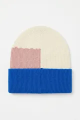 Gorro tipo beanie de tejido de punto acanalado con diseño de bloques de color en tonos crema, rosado y azul.