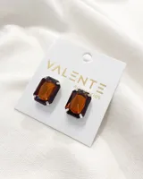 Par de aros de fantasía con forma rectangular y piedra color ámbar engarzada en metal plateado.