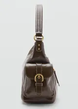 Bolso de hombro estilo hobo en color marrón oscuro con acabado brillante. Presenta un diseño estructurado con múltiples bolsillos exteriores con cierre frontal y laterales, herrajes metálicos dorados y asa fija.