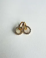 Aritos colgantes dorados con un dije circular de resina transparente rodeado de strass. El aro es de acero quirúrgico.